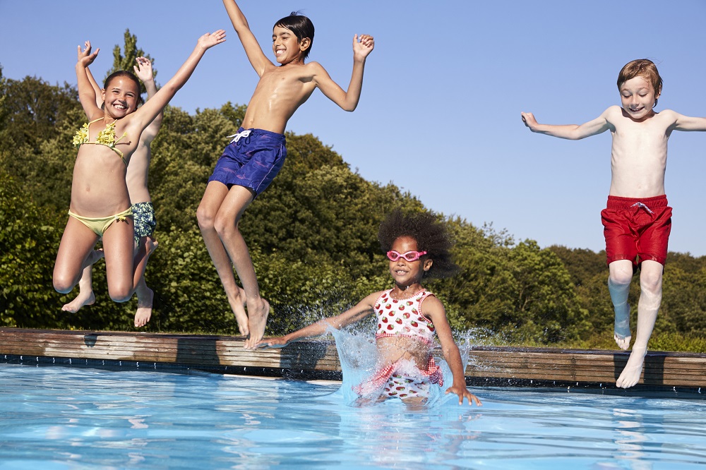 Group Of Children Jumping Into Outdoor Swimming Pool